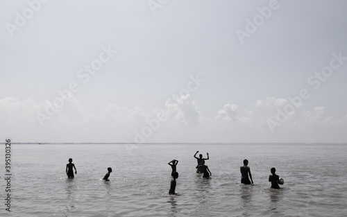 Local young boys taking a bath ,swimming and playing ball in the Padma river in a hot summer day noon