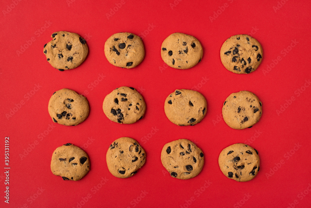 Top flatlay close up above view photo image of tasty cookies with chocolate chips lying in rows isolated bright color red background Top flatlay close up above view photo image of tasty cookies with chocolate chips lying in rows isolated bright color red background