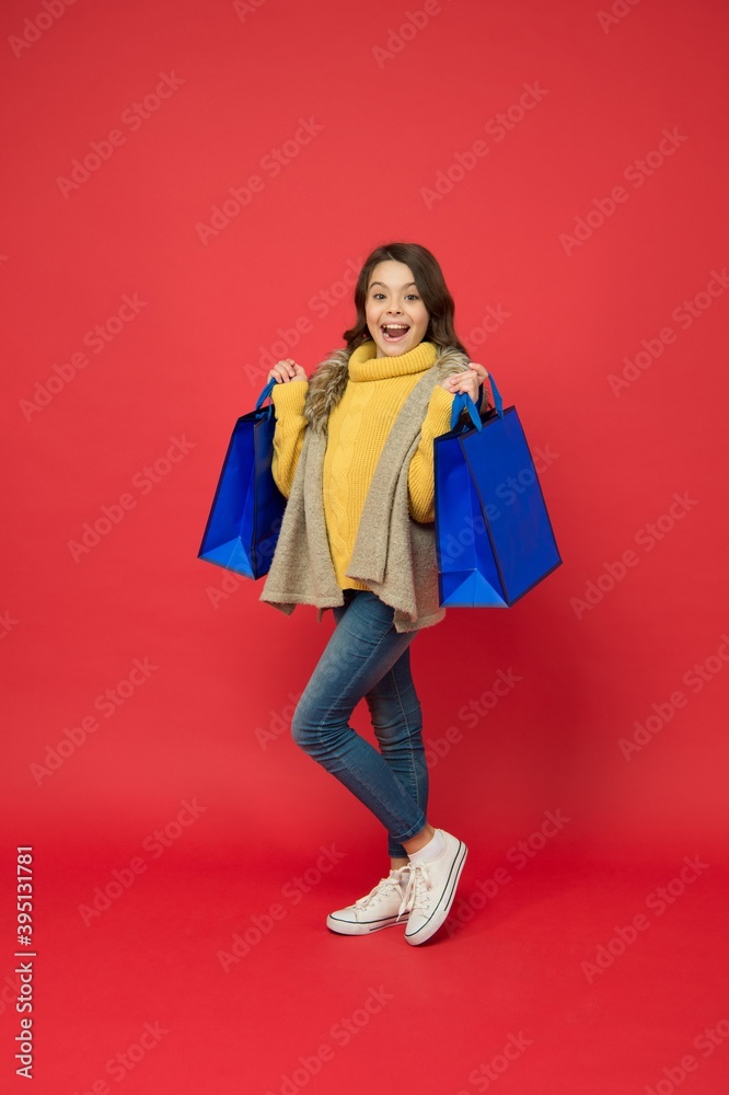 Happy small shopaholic with fashion look carry shopping bags red background, shopaholism Happy small shopaholic with fashion look carry shopping bags red background, shopaholism
