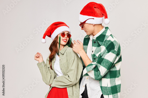 Man and woman in sunglasses Santa hats fashion hugs gray background
