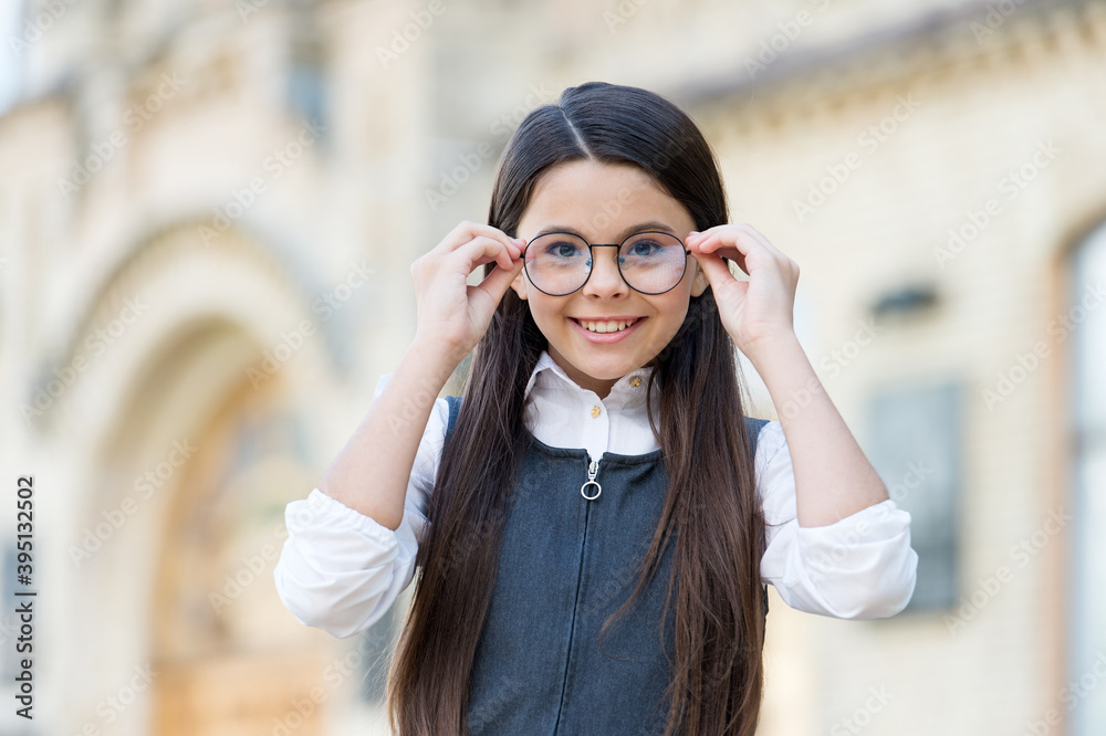 Happy child in school uniform put on fashion eyeglasses to see well outdoors, eyesight