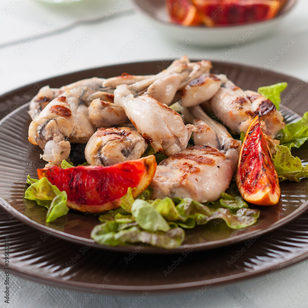 Grilled Frog Legs Garnished with Blood Orange Slices and Fresh Lettuce Grilled Frog Legs Garnished with Blood Orange Slices and Fresh Lettuce