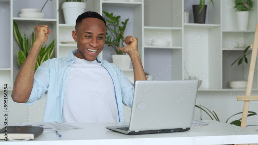 African-American feels happy received great news by internet looks at pc screen raised hands scream with joy celebrating on-line lottery win African-American feels happy received great news by internet looks at pc screen raised hands scream with joy celebrating on-line lottery win