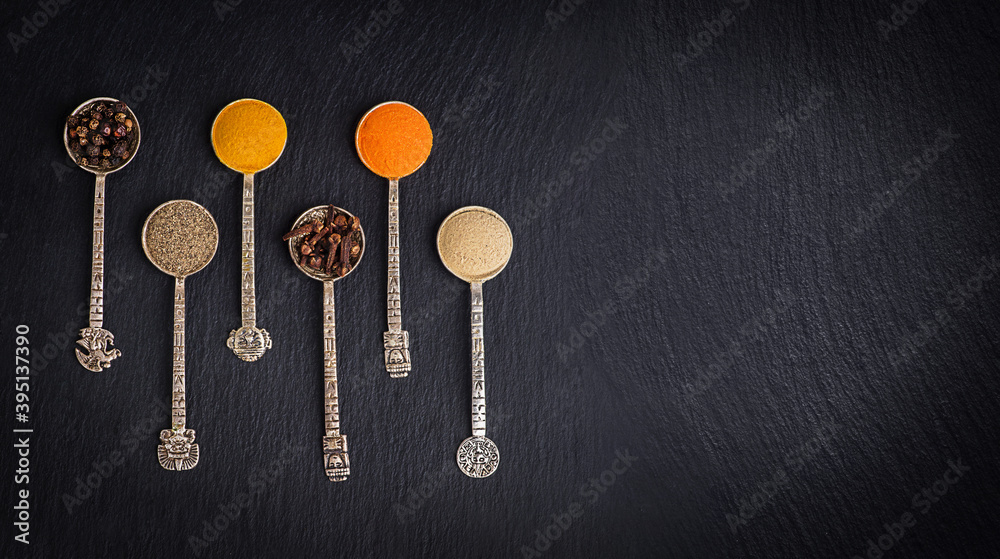 Various herbs and spices on black stone plate. Black pepper, turmeric, ginger, saffron, cloves. Various herbs and spices on black stone plate. Black pepper, turmeric, ginger, saffron, cloves.