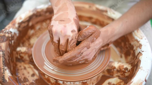 Creating vase of white clay close-up. The sculptor in the workshop makes a jug out of earthenware closeup. Twisted potter's wheel. Master crock. photo