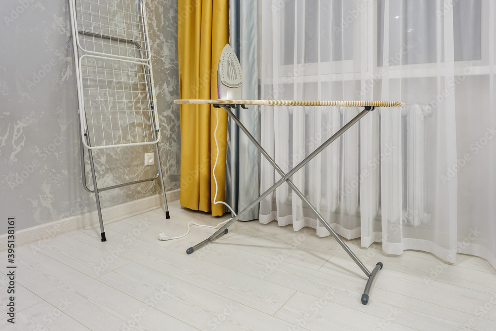modern iron on ironing board in white room
