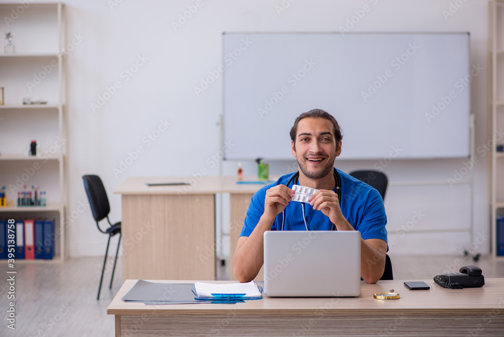 Young male doctor suggesting pills in the clinic Young male doctor suggesting pills in the clinic