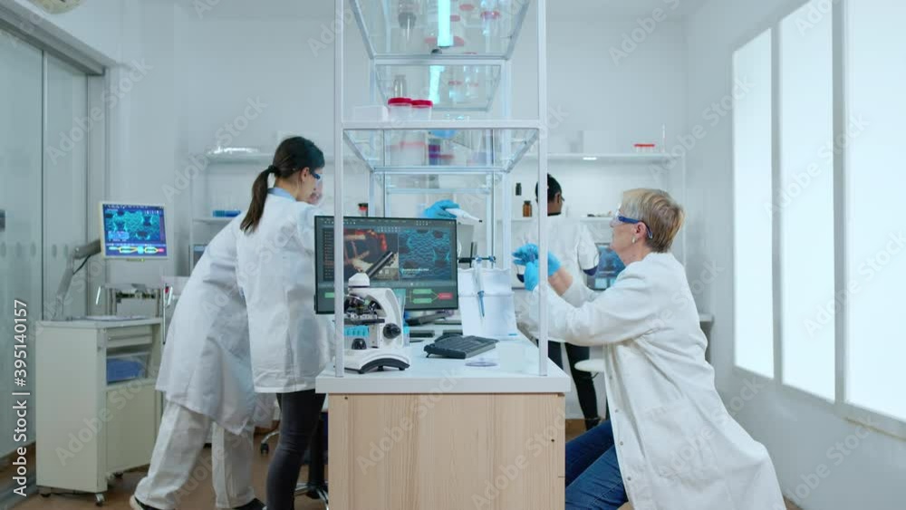 Multiethnic team working in busy modern equipped laboratory wearing white coat. Diverse group of scientists analysing vaccine evolution using high tech for researching treatment against covid19 virus Multiethnic team working in busy modern equipped laboratory wearing white coat. Diverse group of scientists analysing vaccine evolution using high tech for researching treatment against covid19 virus