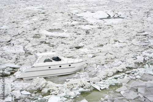 Side view of a trapped boat in the frozen Danube river that is almost completely frozen and full of ice pieces due to an exceptionnaly cold weather over Balkans. photo