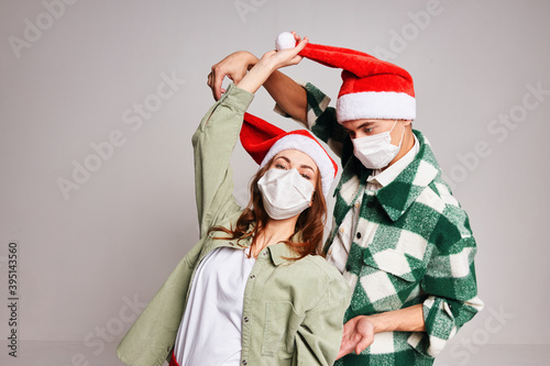 Man and woman having fun together in medical masks holiday Christmas gray background