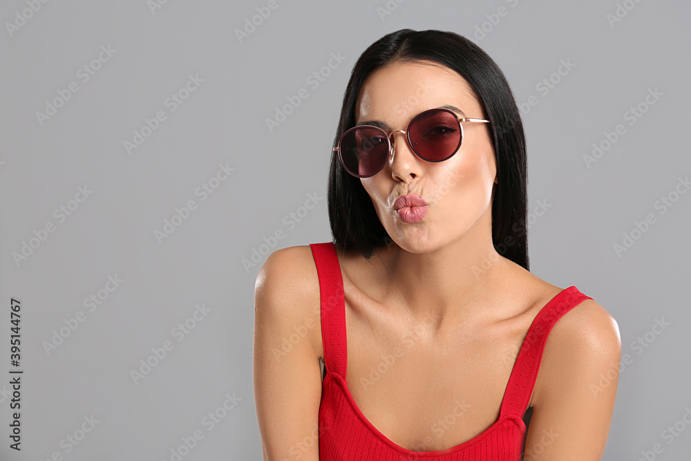 Beautiful woman wearing sunglasses on grey background Beautiful woman wearing sunglasses on grey background