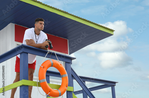Male lifeguard with binocular on watch tower