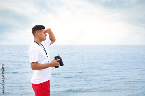 Handsome male lifeguard with binocular near sea