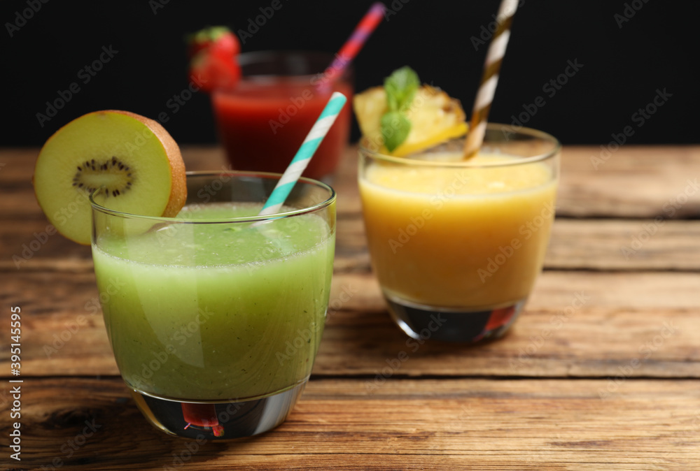 Delicious colorful juices in glasses on wooden table, closeup Delicious colorful juices in glasses on wooden table, closeup