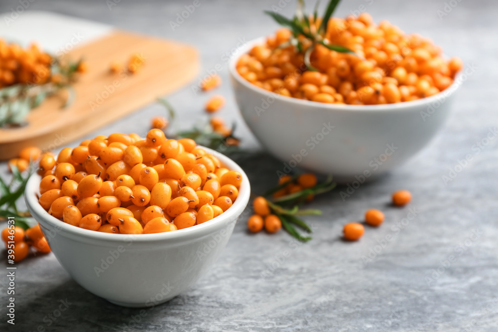 Fresh ripe sea buckthorn in bowl on grey table Fresh ripe sea buckthorn in bowl on grey table