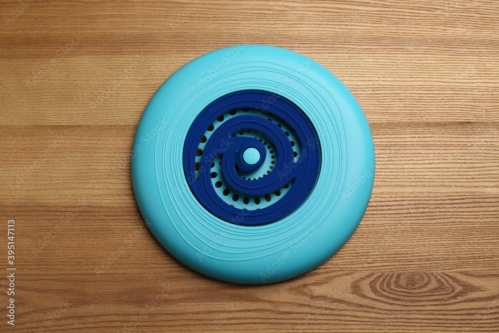 Blue plastic frisbee disk on wooden background, top view