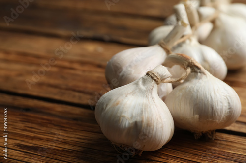 Fresh organic garlic on wooden table  closeup. Space for text