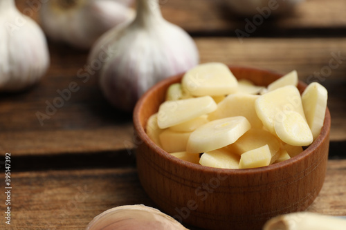 Fresh chopped garlic in bowl on wooden table, closeup. Organic product