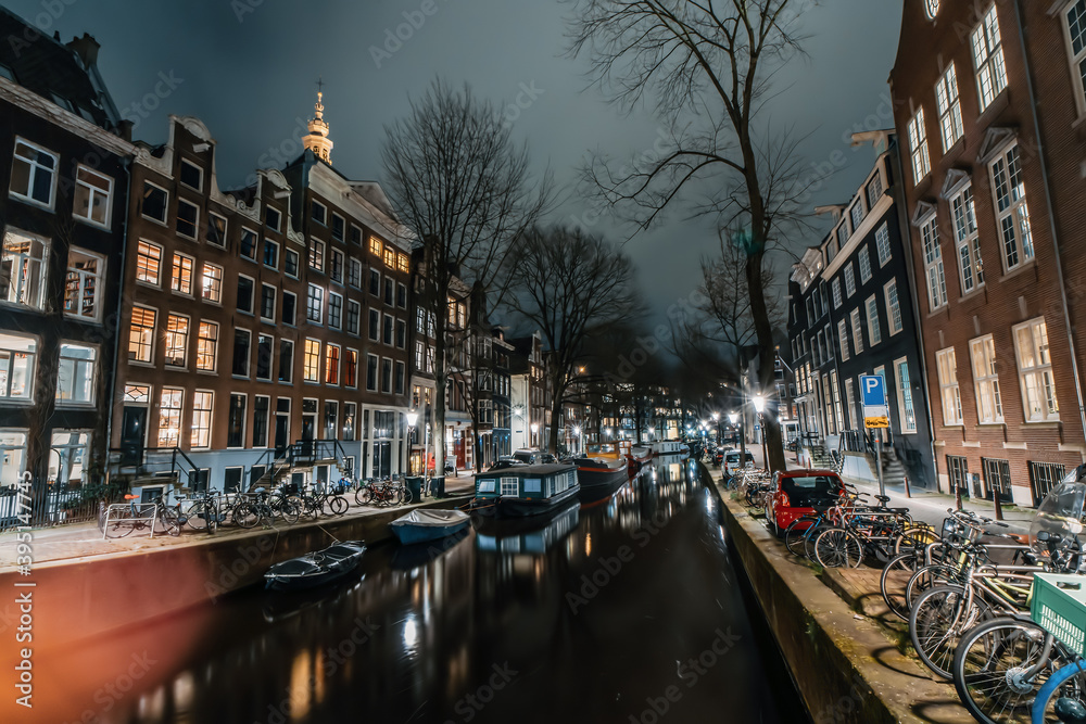 Amsterdam night city water canal with evening lights reflection and old houses, Amsterdam, Netherlands.