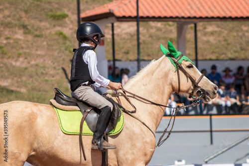 Menino de capacete cavalgando cavalo caramelo com touca verde photo