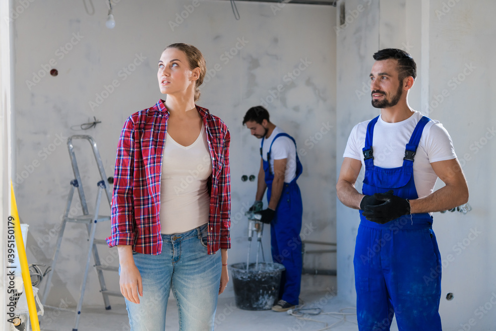 A customer monitors the renovation process in the apartment and talks to the worker A customer monitors the renovation process in the apartment and talks to the worker