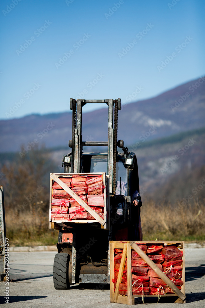Forklift picking up pallets of firewood ready for transport Forklift picking up pallets of firewood ready for transport