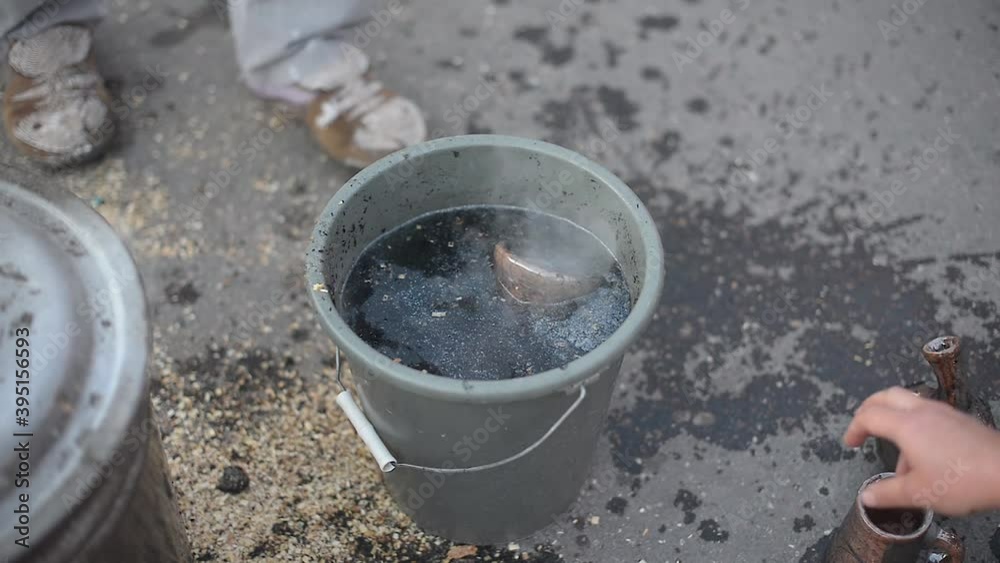 A potter is cooling the finished clay jug in a bucket of water A potter is cooling the finished clay jug in a bucket of water