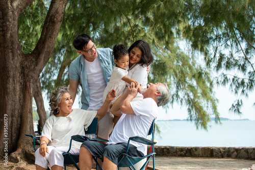Group of Healthy multi generation Asian family enjoy picnic travel together on the beach. Parents with cute child girl and healthy senior grandparents relax and having fun on summer holiday vacation © CandyRetriever 
