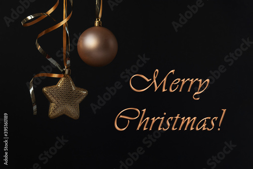 Golden Christmas decorations and Merry Christmas text on black background.