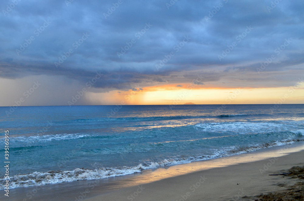 Rain storm cell and sunset on view at a beach overlooking the Mona Passage and Caribbean Sea.  Rincon, Puerto Rico.