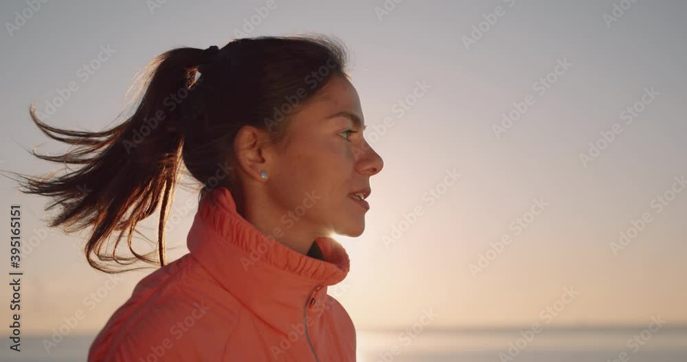 Close up of woman in sports uniform running on sunrise background over sea. Motivation of sports. Active lifestyle. Close up of woman in sports uniform running on sunrise background over sea. Motivation of sports. Active lifestyle.