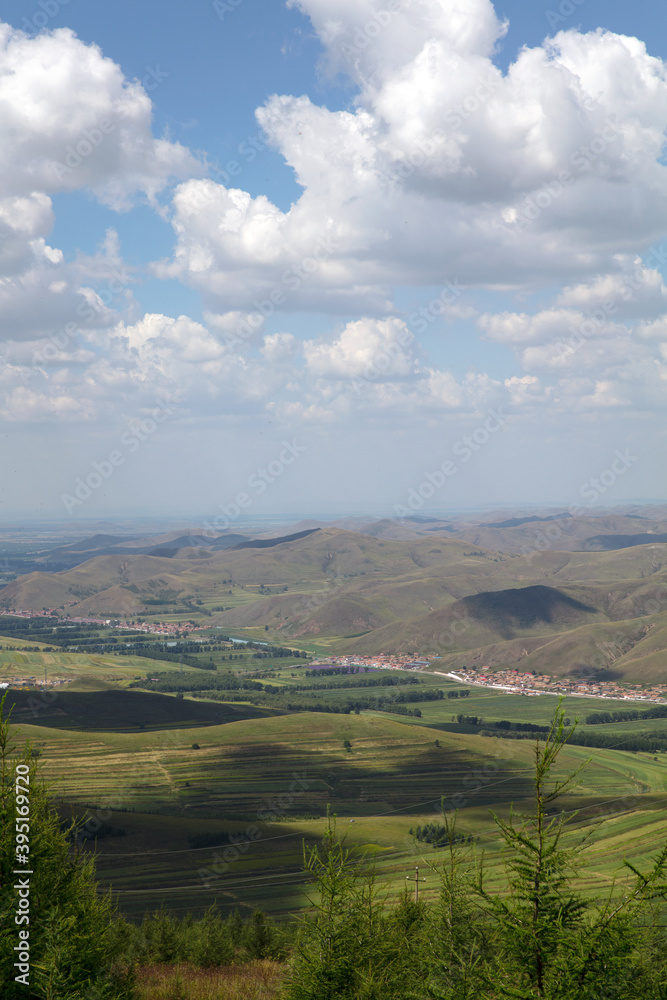The top of the mountain in Zhangbei County looks at the grassland scenery under the blue sky and white clouds