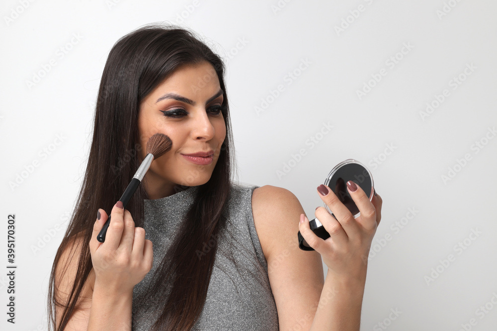 Beautiful girl putting on makeup on white background Beautiful girl putting on makeup on white background