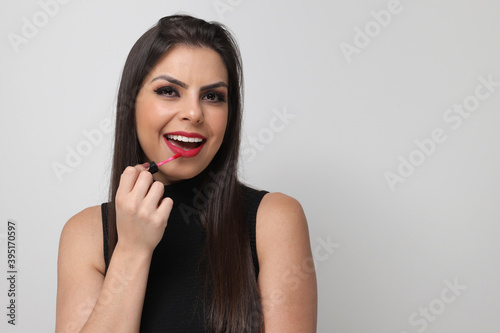 Beautiful girl putting on makeup on white background