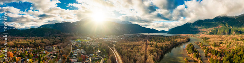 Aerial panoramic view of a small town with Chief Mountain in the background during a sunny sunrise. Taken in Squamish  North of Vancouver  British Columbia  Canada.