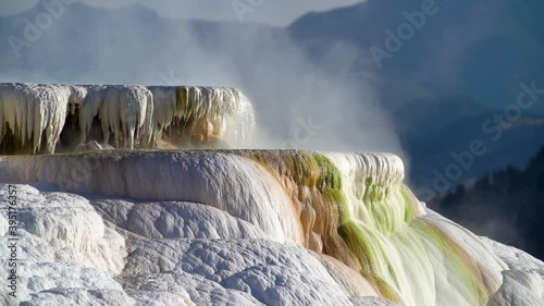 Flowing water and steam rising from Mammoth Hot Springs during early morning light at Yellowstone National Park.