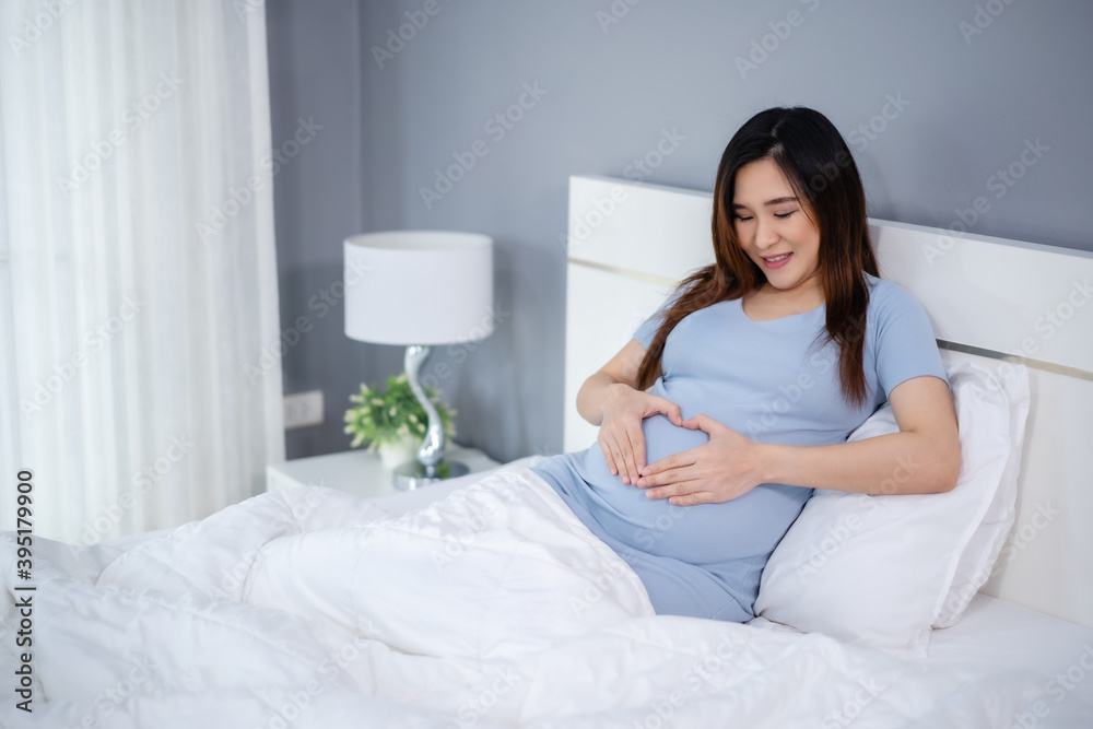 pregnant woman making hand heart gesture in a bed pregnant woman making hand heart gesture in a bed