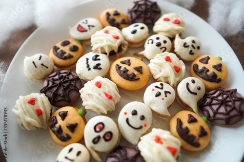 Homemade Halloween macarons and cookies on a white plate. Decorations include jack-o -lanterns  ghosts  mummies  and spider webs. 