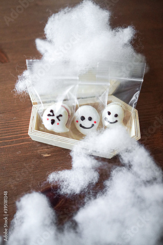 Three decorated ghost macarons in a wooden coffin.