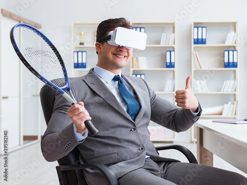 Businessman playing virtual reality tennis in office with VR gog