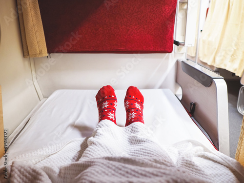 Tourist wearing red socks with Cheistmas pattern selfie feet on bed in train travelling. photo