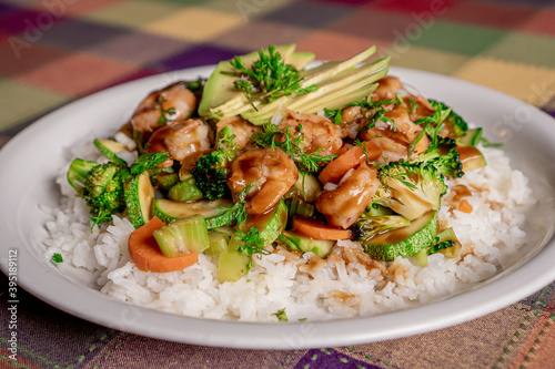 Delicious shrimp teriyaki with broccoli, pumpkin, carrot and rice in oyster sauce on a white plate.