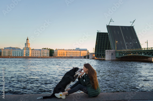 a girl and a dog on the background of drawbridges in St. Petersburg. Traveling with pet in the city