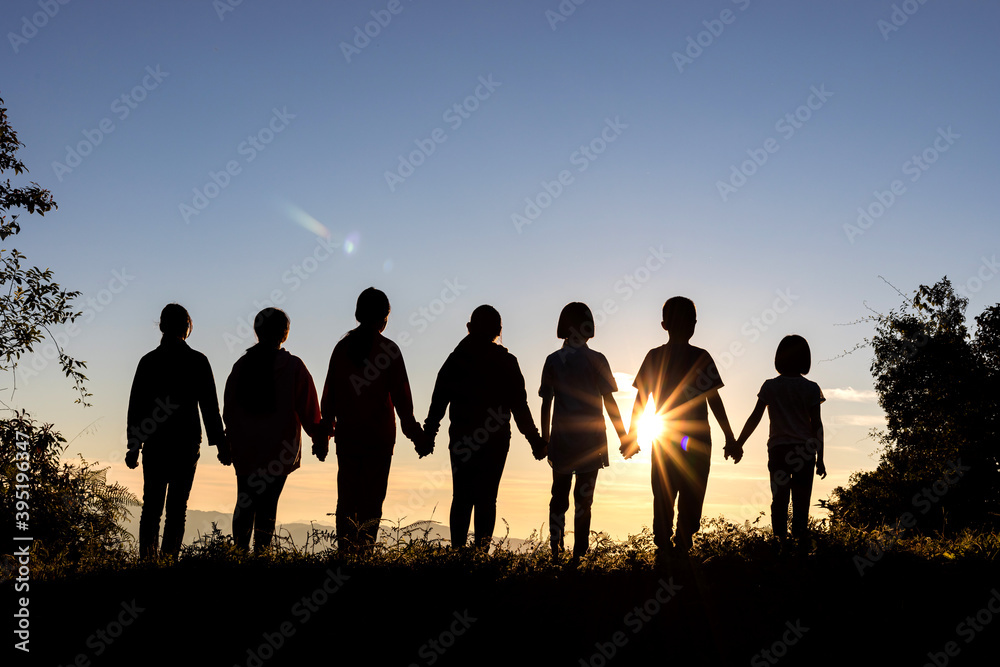 Silhouette of group children standing on mountain at sunset