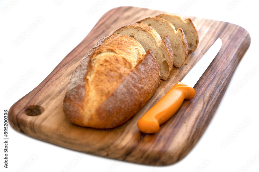 Fresh daily baking healthy plain sourdough loaf placing on top of cutting wooden board with a sharp knife sliding into small pieces  isolated white background 