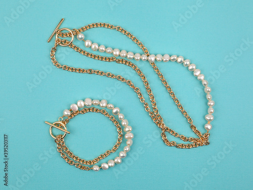 Luxury elegant baroque pearl necklace and bracelet on bright turquoise textured background