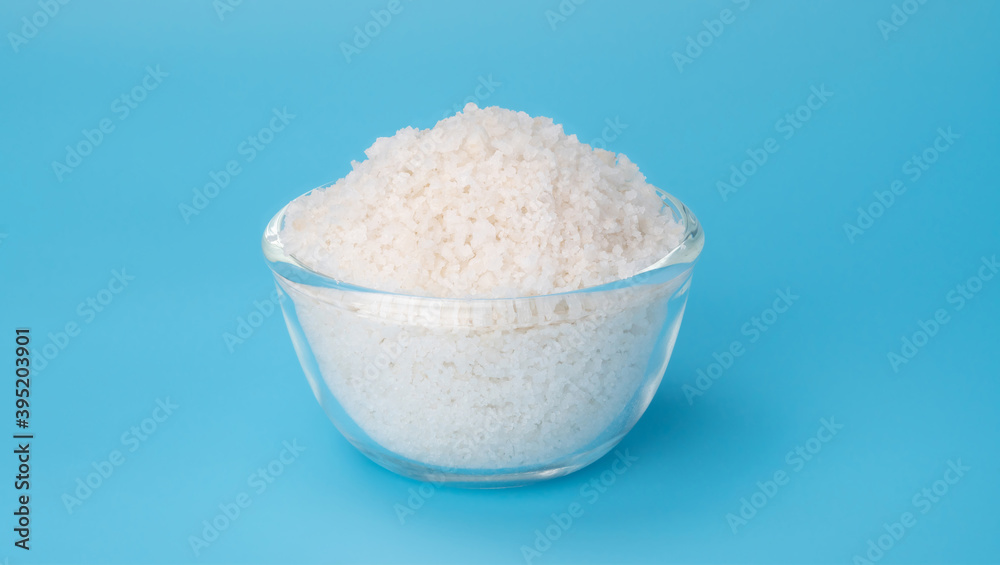 White flower of salt in a bowl on a blue background. White flower of salt in a bowl on a blue background.