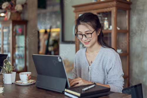 Attractive asian woman working with a digital tablet in a coffee shop.