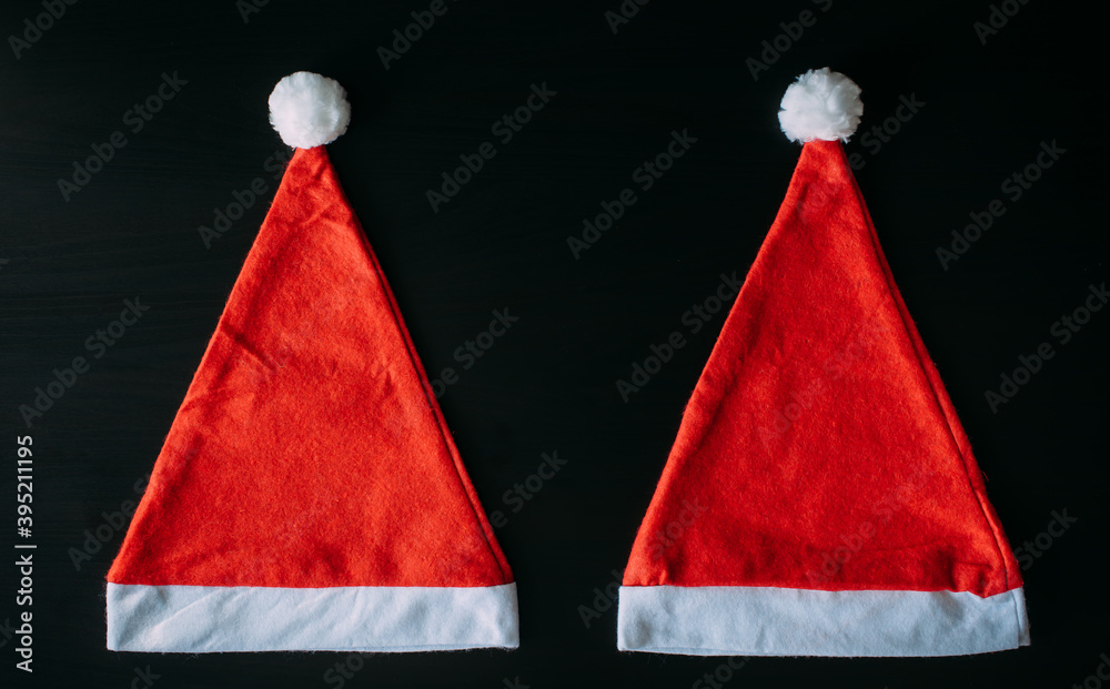 Two red Santa Claus hat isolated on black background with copy space. Father Christmas caps, close up. New year concept. Two red Santa Claus hat isolated on black background with copy space. Father Christmas caps, close up. New year concept.