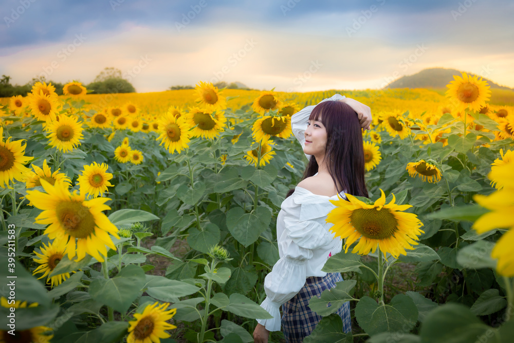 Happy enjoy summer girl in sunflower field in spring. Asian young woman joyful and smiling at sunset time Happy enjoy summer girl in sunflower field in spring. Asian young woman joyful and smiling at sunset time